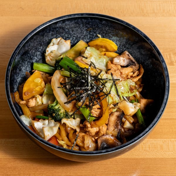 Stir-fried noodles with chicken, broccoli, cabbage, mushrooms, and bell peppers, topped with nori strips.